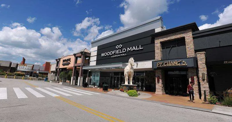 Exterior view of Woodfield Mall in Schaumburg, IL featuring the main entrance, P.F. Chang’s restaurant, and a sunny shopping plaza."